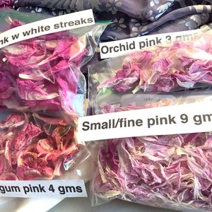 May include: Four bags of dried flower petals in various shades of pink. The bags are labeled with the color and weight of the petals. The labels read: "Bright pink w white streaks", "Bubblegum pink 4 gms", "Orchid pink 3 gms", and "Small/fine pink 9 gms".