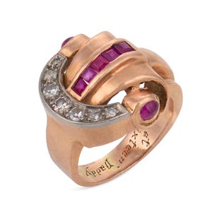 Puede incluir: Un anillo de oro rosa con una hilera curva de cinco rubíes rojos de corte cuadrado, una sección en forma de media luna con seis diamantes blancos redondos y un rubí cabujón redondo. El interior del aro tiene grabado el texto Sweet Sixteen Daddy.