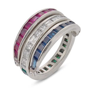 Peut inclure: Une bague multi-anneaux argentée composée de trois rangées distinctes de pierres précieuses taille baguette serties en rail. La rangée supérieure contient des pierres rouges, la rangée centrale des pierres blanches et la rangée inférieure des bleues.