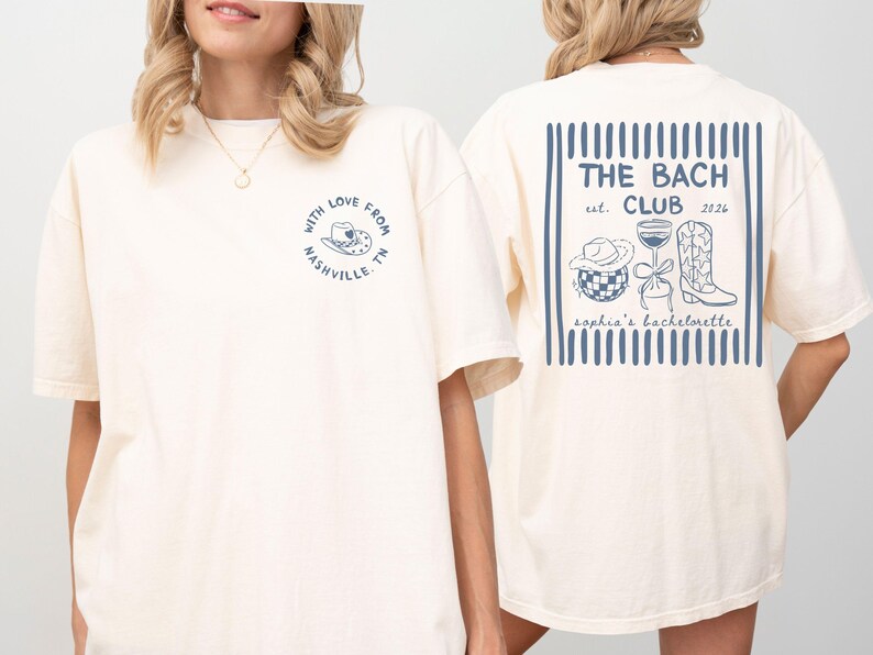 May include: Cream-colored t-shirt with a blue graphic on the front that says "With Love From Nashville TN." The back features a blue design with the text "THE BACH CLUB est. 2026" and illustrations of a cowboy hat, wine glass, and boots.