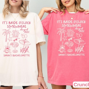 May include: Ivory and Crunchberry-colored t-shirts with the text "IT'S BRIDE O'CLOCK SOMEWHERE August 2026 SARAH'S BACHELORETTE" and a tropical graphic design. The design includes a palm tree, disco ball, cocktail, and beach chair.