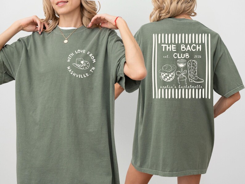 May include: Olive green t-shirt with a white graphic on the front that says "With Love From Nashville TN". The back of the shirt has a white graphic that says "The Bach Club est. 2026" with illustrations of a cowboy hat, disco ball, wine glass, and cowboy boot.
