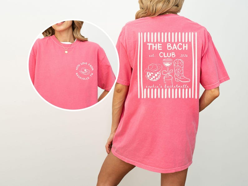 May include: A pink t-shirt with white text and graphics. The back of the shirt features a design with the words "THE BACH CLUB" and the establishment year "2026". The front of the shirt has the words "WITH LOVE FROM NASHVILLE TN".