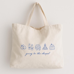 May include: Cream-colored tote bag with blue line art of wedding-related icons, including rings, champagne flutes, a car, a church, and a cake. The words "going to the chapel" are written below the icons.