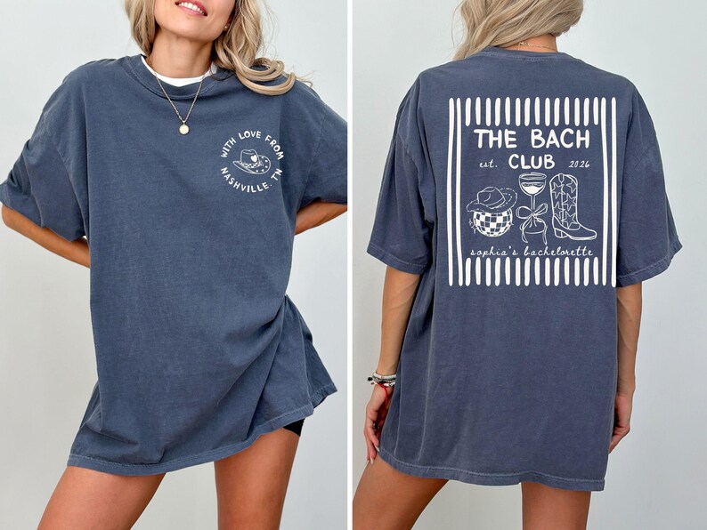 May include: Dark blue t-shirt with white text and graphics. The front says "With Love From Nashville, TN" around a cowboy hat. The back says "THE BACH CLUB est. 2026" with a hat, wine glass, and boots.