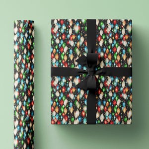 May include: A black gift box with a black ribbon and bow. The box is wrapped in wrapping paper with a pattern of colorful Christmas lights.