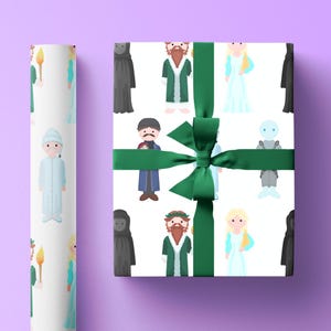 Puede incluir: Papel de regalo blanco con ilustraciones de dibujos animados de personajes de un cuento navideño, con una cinta y un lazo verdes. Un rollo de papel de regalo a juego es visible a la izquierda. Los personajes incluyen un hombre con abrigo verde y una mujer con vestido azul.