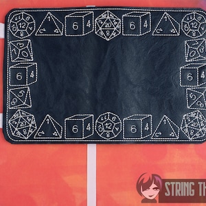 May include: Black leather dice rolling tray with white stitching. The tray is decorated with various dice shapes and numbers. The text "STRING THEORY FABRIC ART" is visible in the bottom right corner.