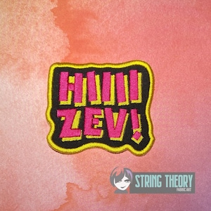 Può includere: Una toppa ricamata con sfondo nero e bordo giallo brillante. La toppa presenta il testo HIIII ZEV! in lettere maiuscole rosa acceso con un contorno giallo, creando un design vivace e ad alto contrasto per l'applicazione su tessuti.