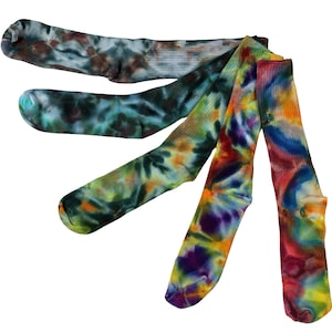 May include: A set of five crew socks featuring various tie-dye patterns. The colors include shades of blue, green, brown, yellow, orange, purple, and red, arranged in a fan-like display against a plain white background.