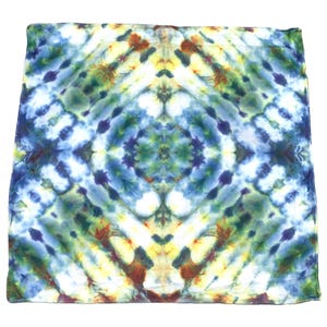 Może przedstawiać: Kwadratowa bandana tie-dye z symetrycznym wzorem. Projekt zawiera mieszankę odcieni niebieskiego, zielonego, żółtego i brązowego. Tkanina jest miękka i wydaje się być bawełniana. Bandana to wszechstronny dodatek.