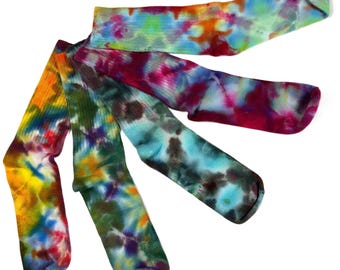 May include: Four crew-length socks featuring a vibrant tie-dye pattern. The socks display a mix of colors including orange, yellow, blue, green, purple, and magenta, arranged in swirling, blended designs across the fabric of each individual sock.
