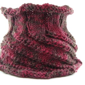 May include: A knitted neck warmer in shades of burgundy and brown. The fabric is textured and has a ribbing pattern.