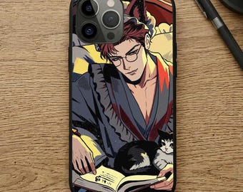 May include: A black smartphone case featuring a graphic illustration of a person with dark hair, glasses, and animal ears, wearing a dark robe while reading a book with a black and white cat resting on their lap. The art style uses bold lines and colors.