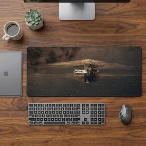 Può includere: Configurazione della scrivania del computer su una superficie in legno. Include un ampio tappetino per mouse rettangolare con un'immagine del paesaggio, una tastiera, un mouse, un monitor, una tazza, una pianta succulenta e un tablet.