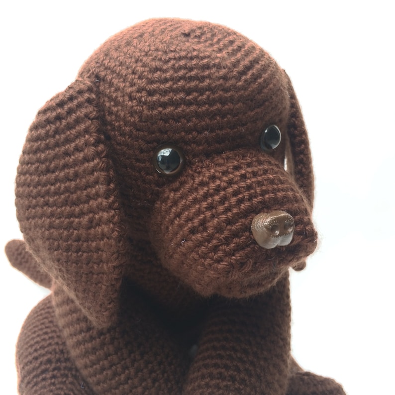 May include: A brown crocheted dog toy with black eyes and a brown plastic nose.
