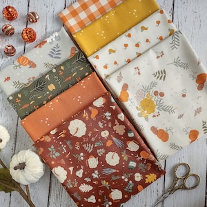 May include: A set of eight fabric squares featuring various autumnal patterns. The patterns include a gingham check, a solid yellow with white stars, a white background with orange pumpkins, a white background with green leaves and orange pumpkins, a rust orange background with white stars, a rust orange background with white pumpkins, a white background with green leaves and orange pumpkins, and a rust orange background with white pumpkins and other fall-themed elements.