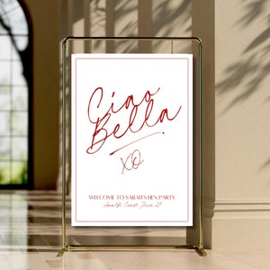 May include: A white sign with a red border and red text that says "Ciao Bella" with an "XO" underneath. The sign also says "Welcome to Sarah's Hen Party Amalfi Coast June 21st".