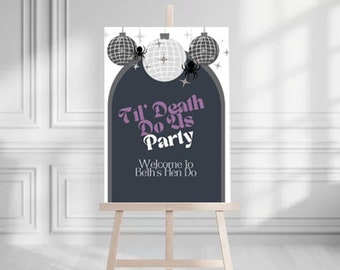 May include: A black and white sign with a purple text overlay that reads "Til' Death Do Us Party" and "Welcome to Beth's Hen Do". The sign is decorated with silver disco balls and black spiders.
