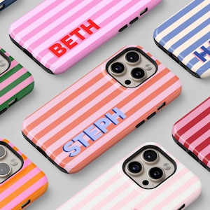 May include: A collection of personalized phone cases with colorful striped designs. Each case features a different name in a bold, contrasting font. The cases are available in various colors, including pink, orange, blue, green, and red.