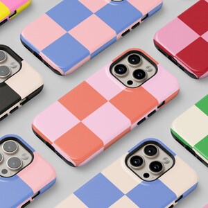May include: A collection of phone cases with checkered patterns in various colors, including pink, blue, green, yellow, and red. The cases are arranged in a grid pattern on a white surface.