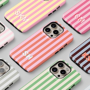 Puede incluir: Una colección de fundas para teléfonos con rayas horizontales en varios colores, incluyendo rosa, verde y azul. Cada funda presenta un monograma único en un color contrastante.