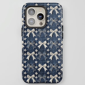 Op de afbeelding: Een blauwe denim telefoonhoes met een wit strikpatroon. De hoes heeft een camera-uitsparing en een zilveren rand.