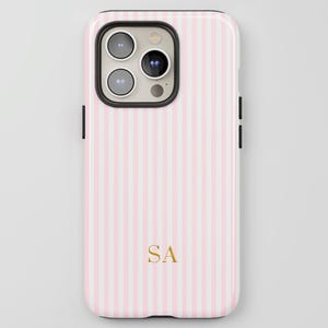 May include: A pink and white striped phone case with gold initials "SA". The case has a glossy finish and a black border around the camera and sides. The phone case is designed to fit a smartphone.