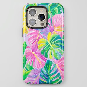Puede incluir: Una funda de teléfono con un vibrante diseño de hojas tropicales. La funda presenta hojas grandes en tonos rosa, verde, amarillo y azul sobre un fondo morado claro. La funda tiene un acabado brillante y un recorte para la cámara.