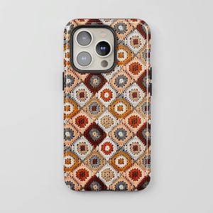 May include: A smartphone case featuring a repeating pattern of square crochet motifs in shades of burnt orange, cream, beige, and dark charcoal gray. The design mimics a classic granny square quilt layout with a textured, woven appearance.