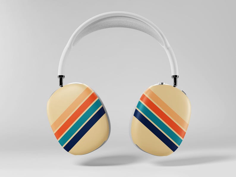 May include: White over-ear headphones with cream-colored earcups. Each earcup features diagonal stripes in orange, teal, and navy blue. The headband is white, and the design has a retro aesthetic.