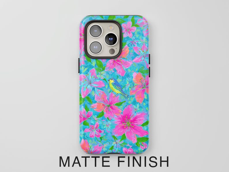May include: A phone case with a vibrant floral design featuring pink flowers, green leaves, and a blue bird against a turquoise background. The case has a matte finish, with the words "MATTE FINISH" at the bottom.