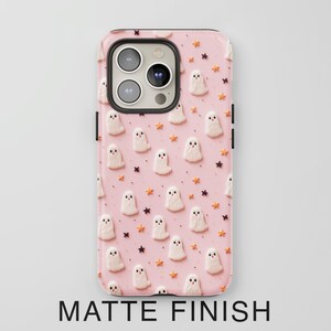May include: A pink phone case with a pattern of white ghosts and orange stars. The case has a matte finish.