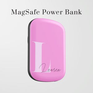 May include: A pink MagSafe power bank with a black border. The power bank has a large white letter "L" and the name "Lauren" in a script font. The text "MagSafe Power Bank" is at the top.