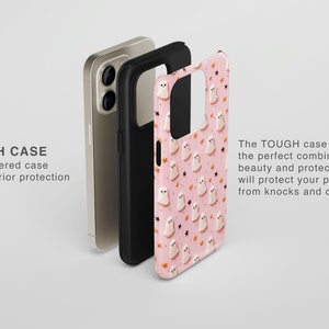May include: A pink phone case with a pattern of white ghosts and orange stars. The case is made of a tough, durable material and provides protection from drops and knocks. The text "TOUGH CASE" is visible on the image.