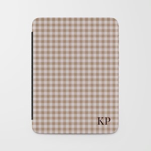 May include: A tan and white gingham pattern tablet case with the initials "KP" in the lower right corner. The case has a black spine and a rounded top edge.