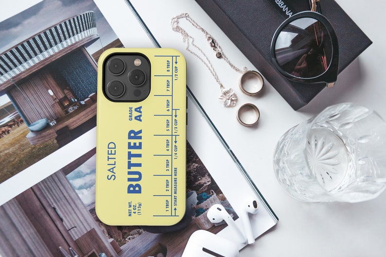 May include: A yellow phone case with a butter stick design. The case has a blue and white label that reads "Salted Butter AA" and includes a measurement guide for tablespoons and cups. The case is designed for an iPhone.