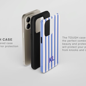 May include: A dual-layered phone case featuring a light blue and cream vertical striped pattern with the monogram KL in dark blue. The set includes a metallic phone, a black inner shell, and the patterned outer shell with text TOUGH CASE.