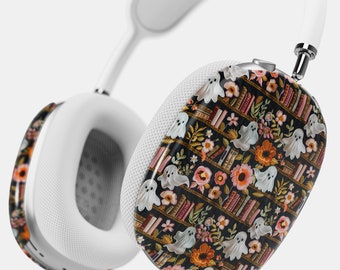 May include: White wireless headphones with a black and white patterned design featuring ghosts, books, and flowers. The pattern is on the earcups of the headphones.