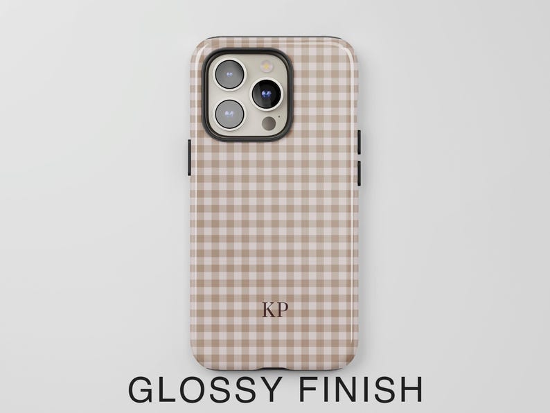 Puede incluir: Una funda para smartphone con acabado brillante que presenta un patr&oacute;n de cuadros vichy en color beige claro y blanco. La funda incluye un recorte para la c&aacute;mara con tres lentes y un flash. Las letras KP est&aacute;n impresas en la parte inferior central.