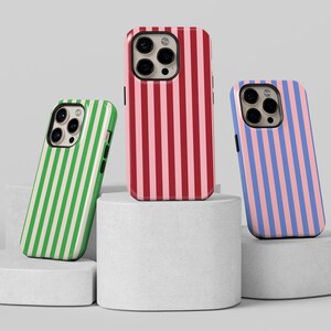 May include: Three phone cases with different striped patterns. The cases are red and pink, green and white, and blue and pink.