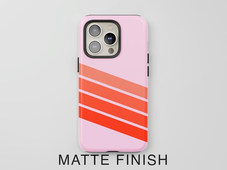 May include: A light pink smartphone case with a matte finish featuring three diagonal stripes in varying shades of orange and red across the lower portion. The case has a black camera module cutout with three circular lenses and a flash.