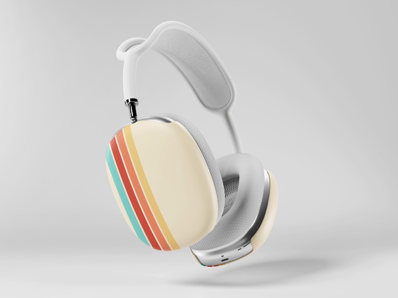 May include: Cream-colored over-ear headphones with a retro stripe design in red, orange, yellow, and teal. The headphones have a white headband and earcups with a silver trim. The overall design is modern with a vintage flair.