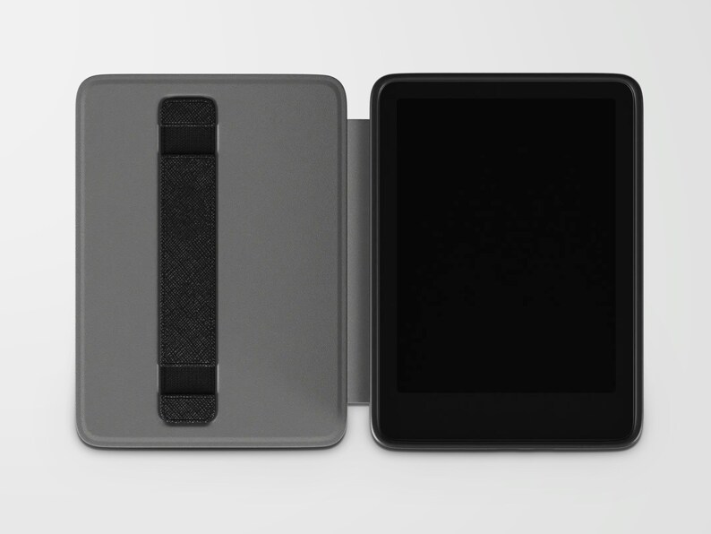 May include: A gray tablet case with a black hand strap is open next to a black tablet. The case is rectangular and has a textured surface. The tablet has a black screen and a black border.