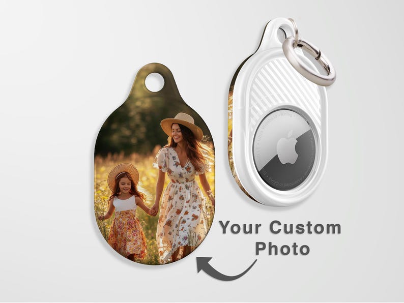 May include: Custom photo keychain with a picture of a woman and child in a field. The keychain is oval-shaped with a hole at the top. A white AirTag with a silver ring is also shown. Text reads "Your Custom Photo".