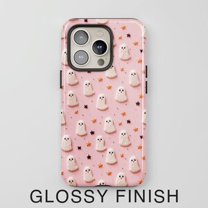 May include: Pink phone case with a pattern of white ghosts and orange stars. The case has a glossy finish.