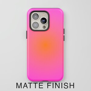 May include: A matte finish phone case with a vibrant pink and orange gradient. The case has a black border around the camera and sides. The text "MATTE FINISH" is displayed at the bottom.
