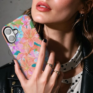 May include: A floral phone case featuring a vibrant design of pink, orange, and blue lilies. The case has a glossy finish and a black camera module. The overall theme is nature and art.