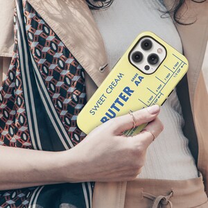 May include: A yellow phone case with a vintage butter stick design. The case features the text "Sweet Cream Butter AA Grade" and a measurement chart for tablespoons and cups.