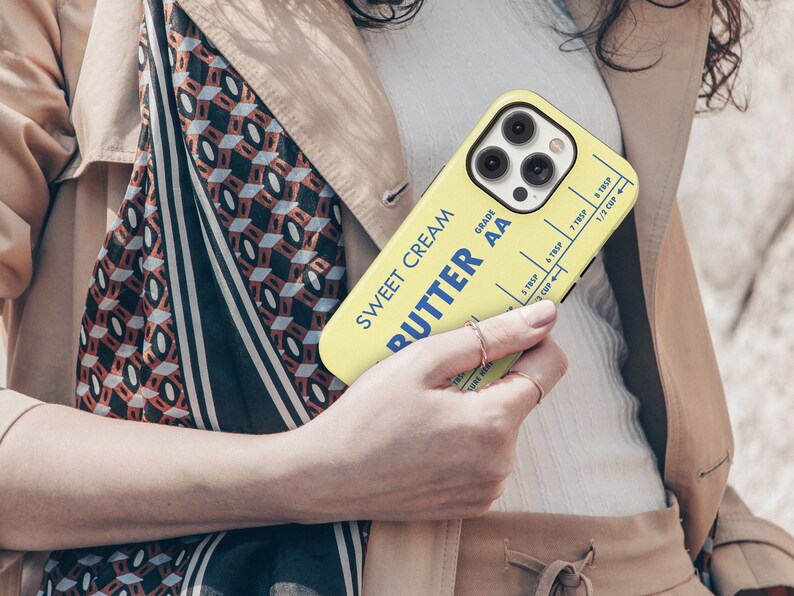 May include: A yellow phone case with a vintage butter stick design. The case features the text "Sweet Cream Butter AA Grade" and a measurement chart for tablespoons and cups.